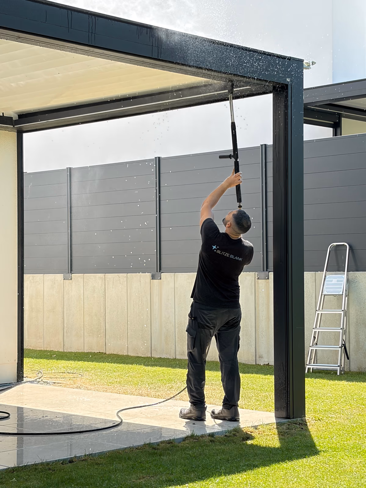 Blitzeblank Mitarbeiter reinigt ein Pergola-Dach mit der Hochdruck-Teleskoplanze