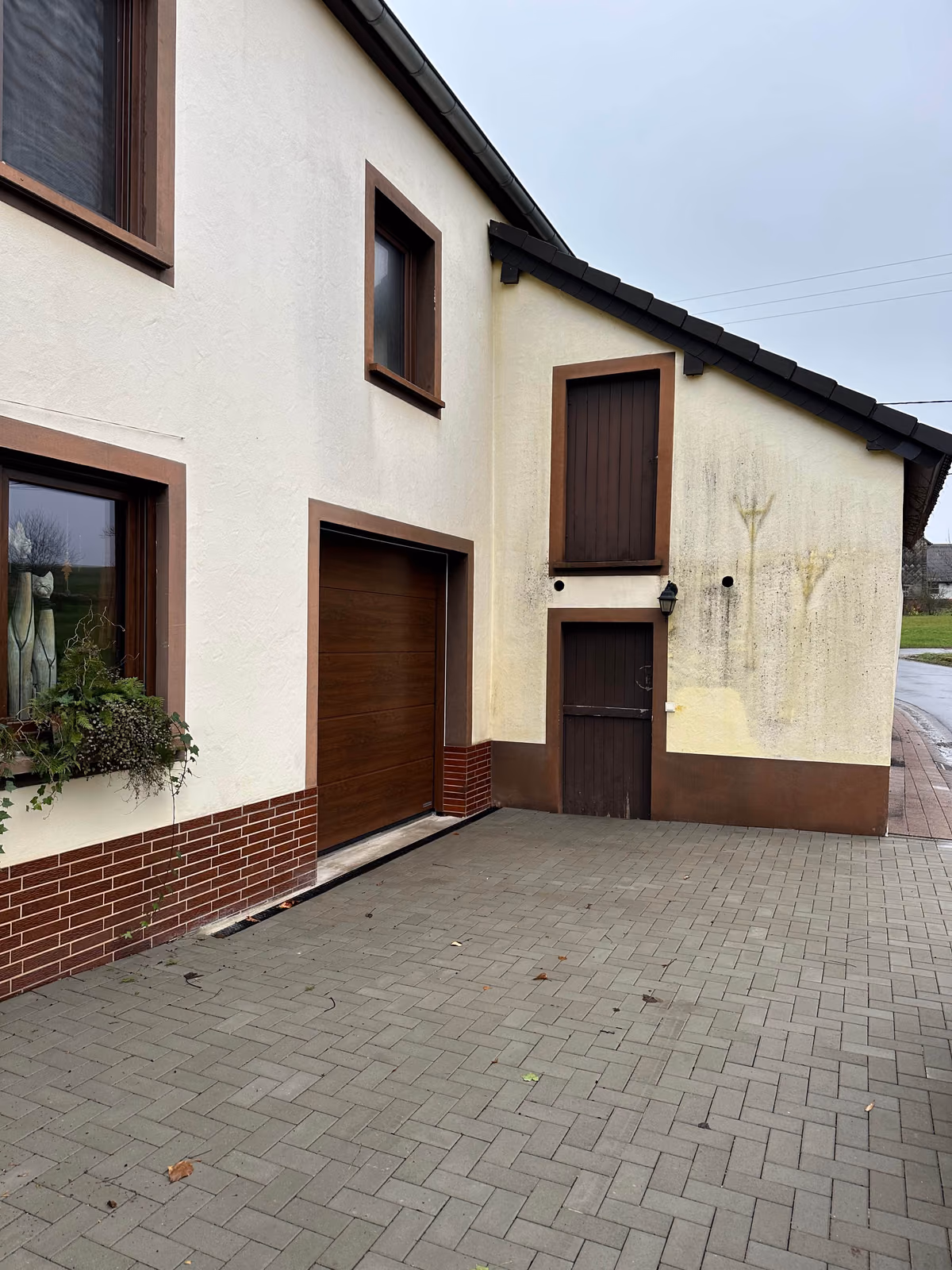 Gelbe Einfamilienhaus-Fassade mit veralgtem, verschmutztem Giebel vor der Reinigung