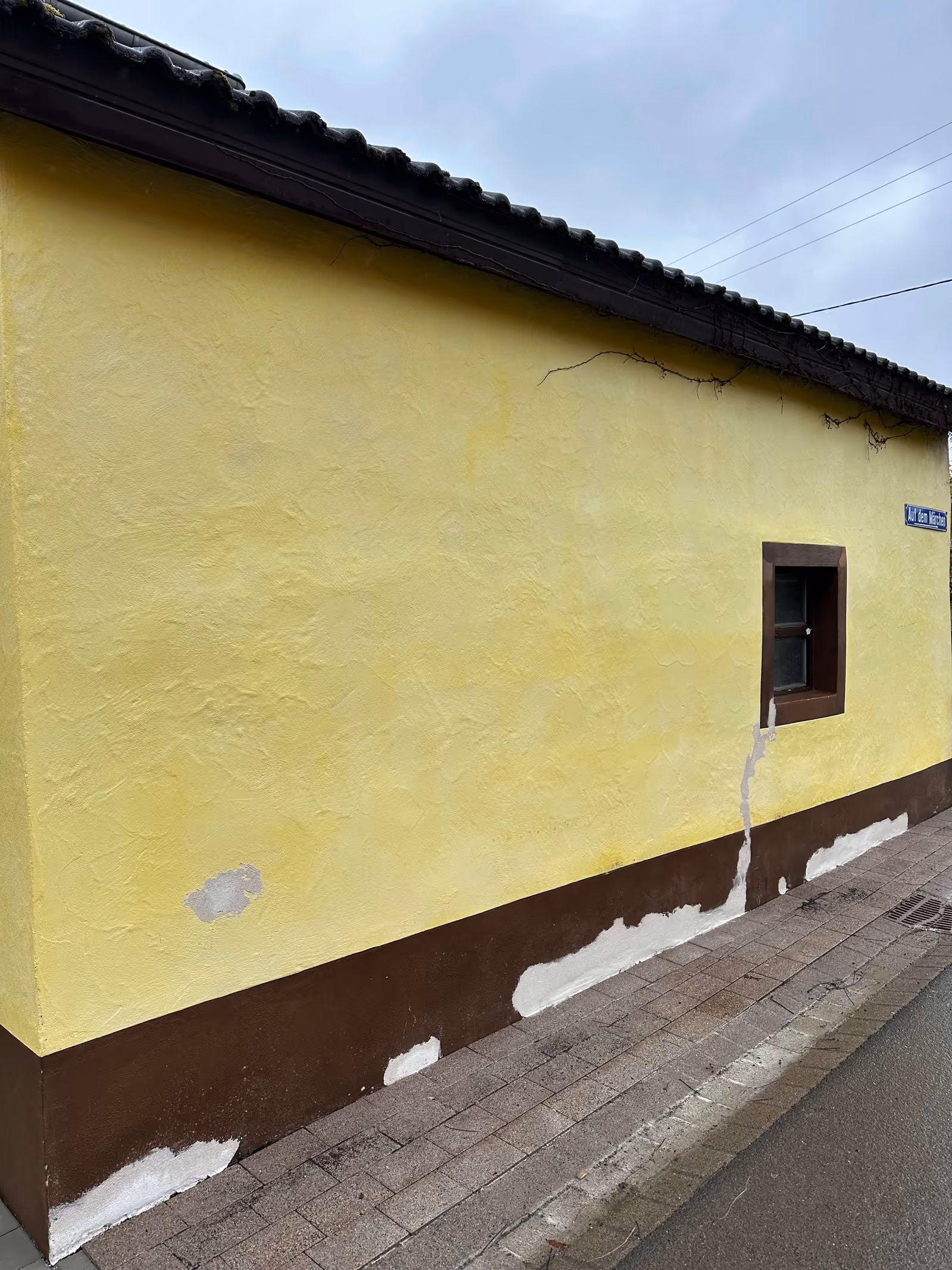 Frisch gereinigte, leuchtend gelbe Hausfassade mit sauberem Sockel nach der Fassadenreinigung