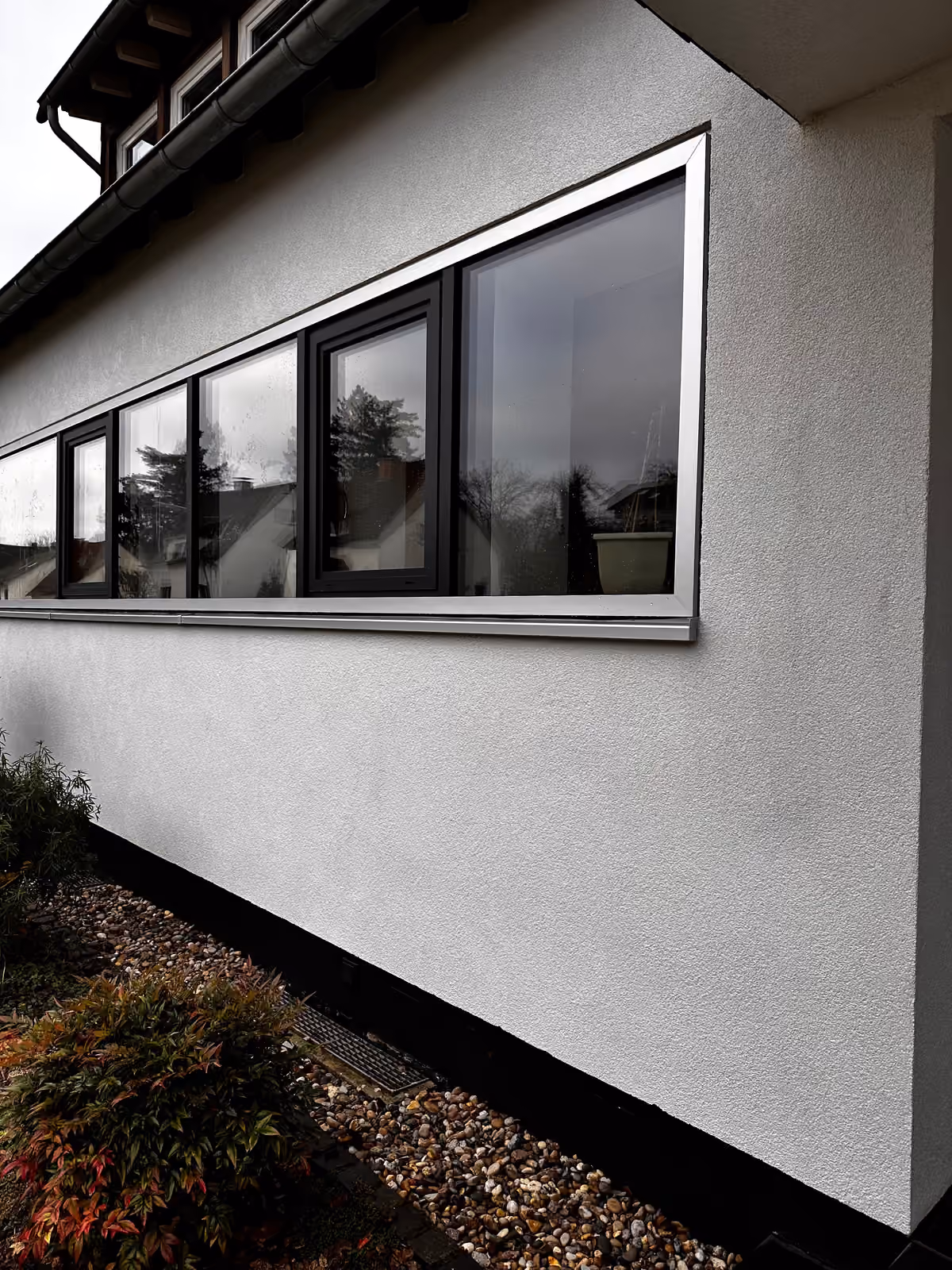 Gereinigte, helle Putzfassade mit Fensterband nach der Reinigung