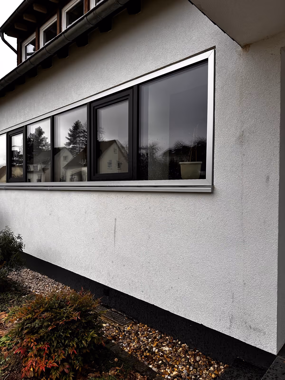 Verschmutzte Putzfassade mit Fensterband und dunklen Ablagerungen vor der Reinigung