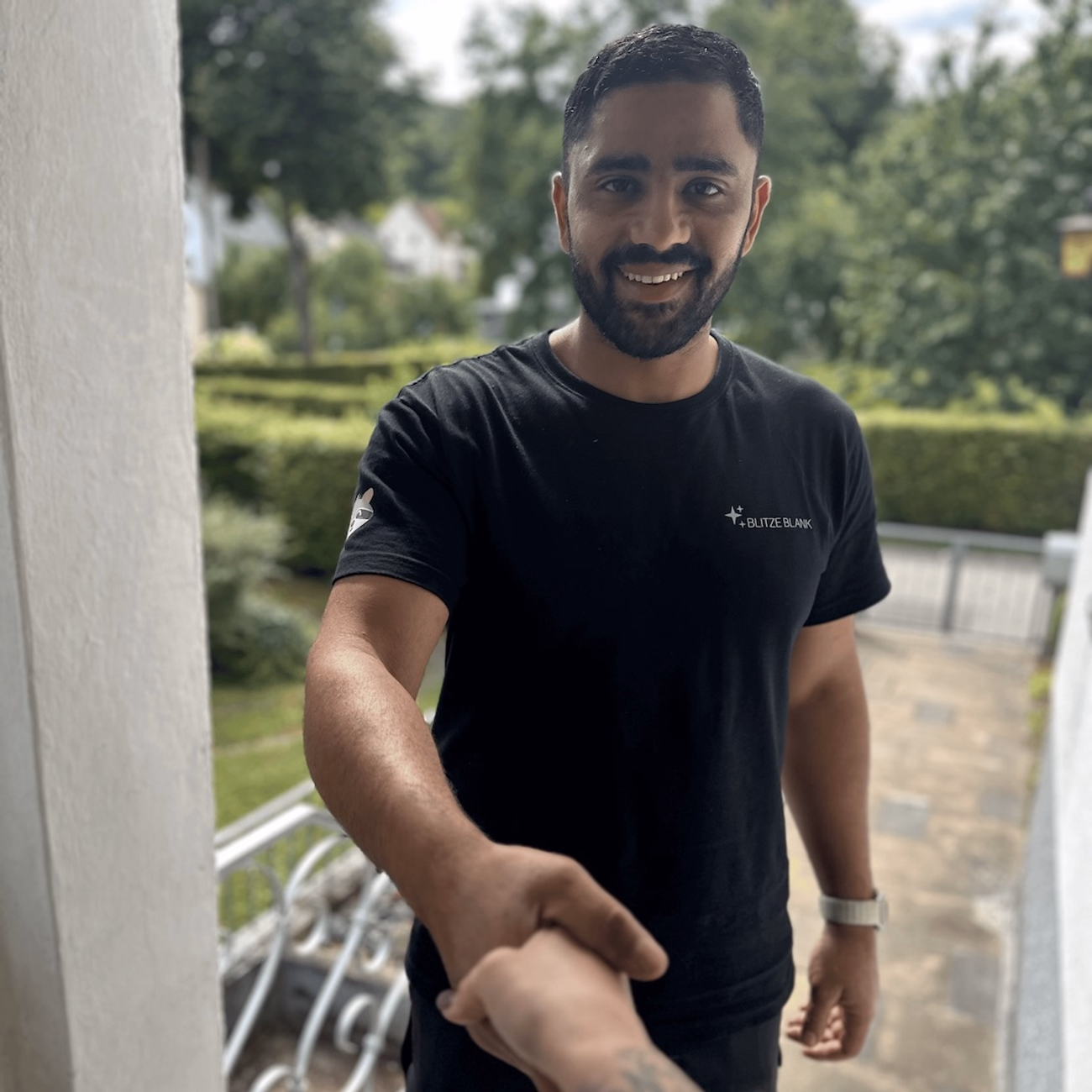 Mustapha El-Ali, founder and managing director of Blitzeblank, in a black company shirt with an outstretched hand in greeting